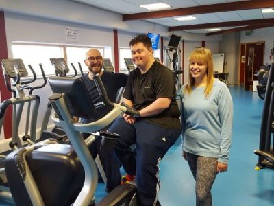 <strong>Carlisle Mencap</strong><br/>Service user Stuart on an exercise bike at the Carlisle Youth Zone gym with our team leaders Dan and Rebecca